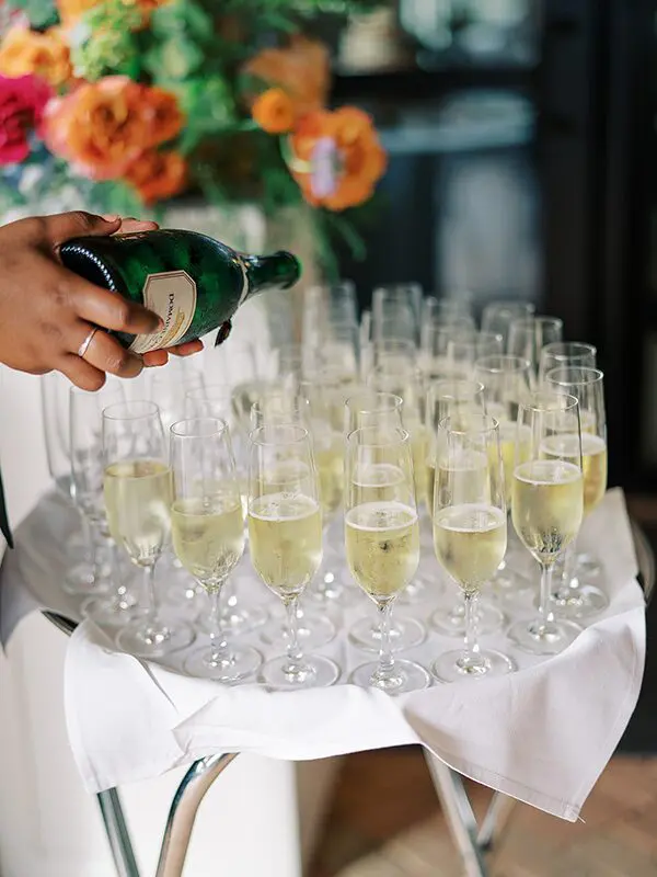 A person pouring champagne into glasses on a table.