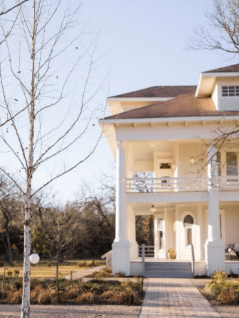 Large white house with porch and columns.