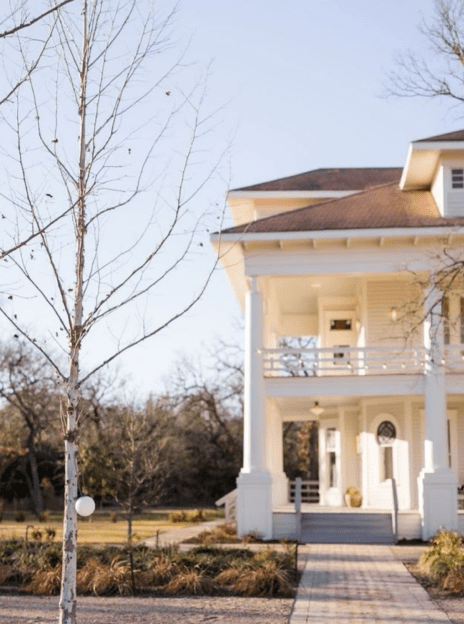 A white house with a tree in the background.