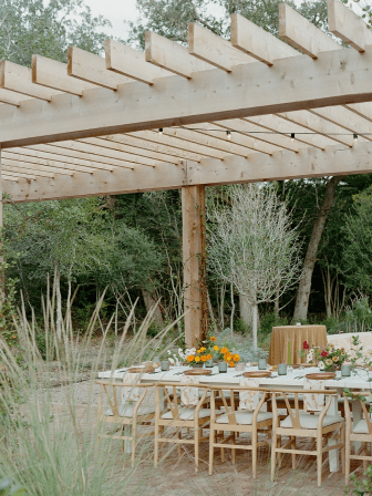 A table with flowers and chairs in the middle of an outdoor setting.