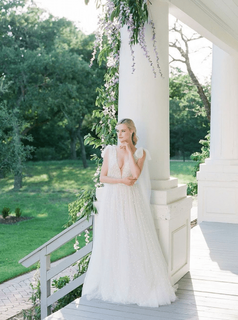 A woman in white dress standing next to a pillar.