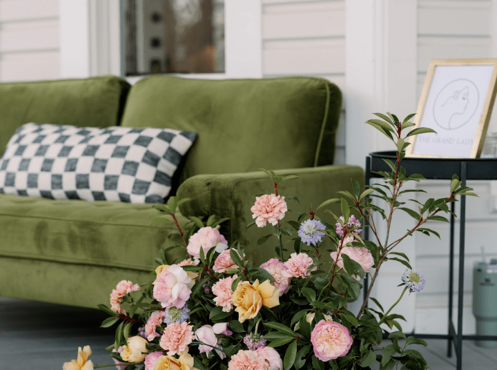 A green couch and some flowers on the ground