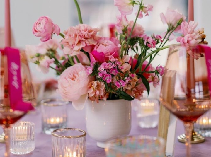 A table with pink flowers and candles on it.