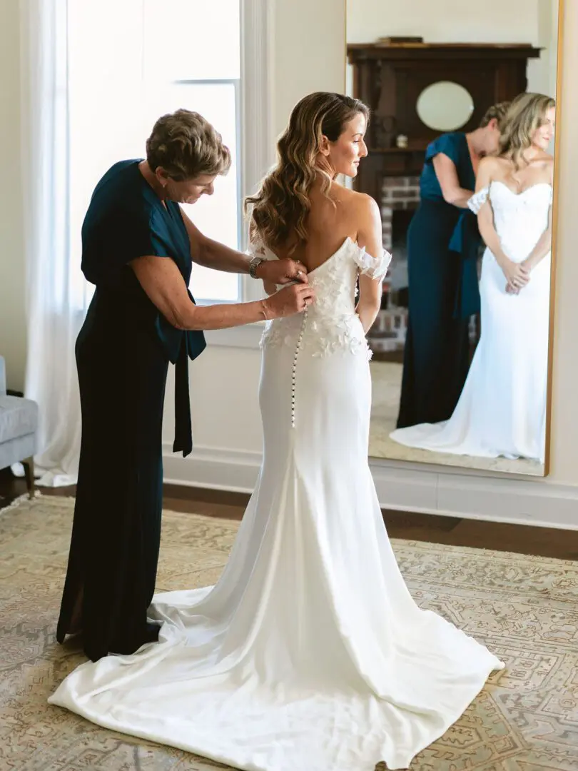 A woman helping another woman with her dress