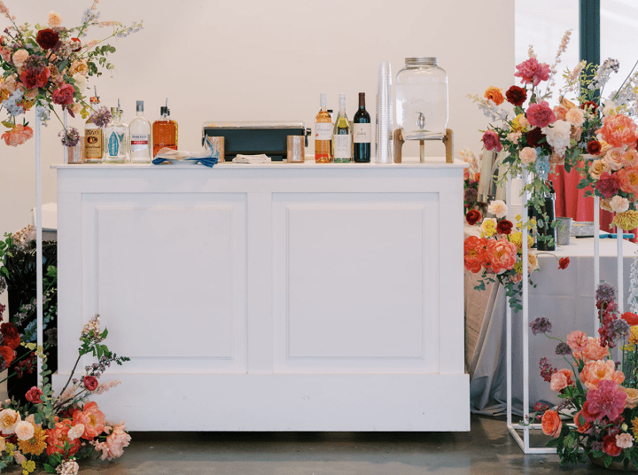 A white bar with bottles and flowers on it.