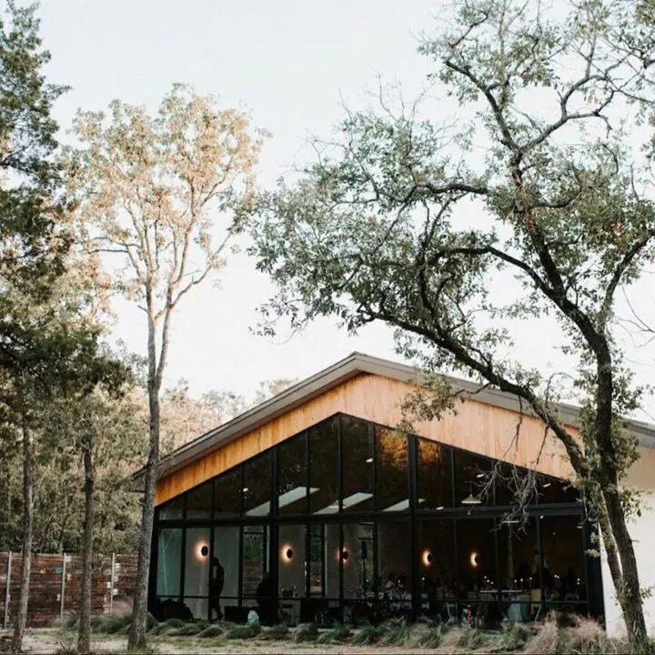 A building with trees in the background and some lights on. It is outside. There are no people around it