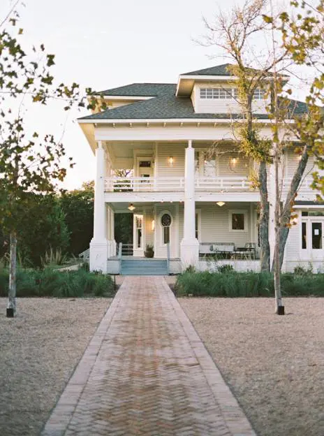 Brick path to large white house.