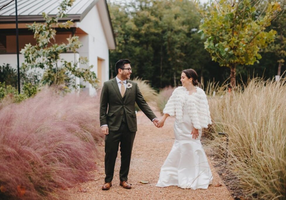 A man and woman holding hands while walking down the road.