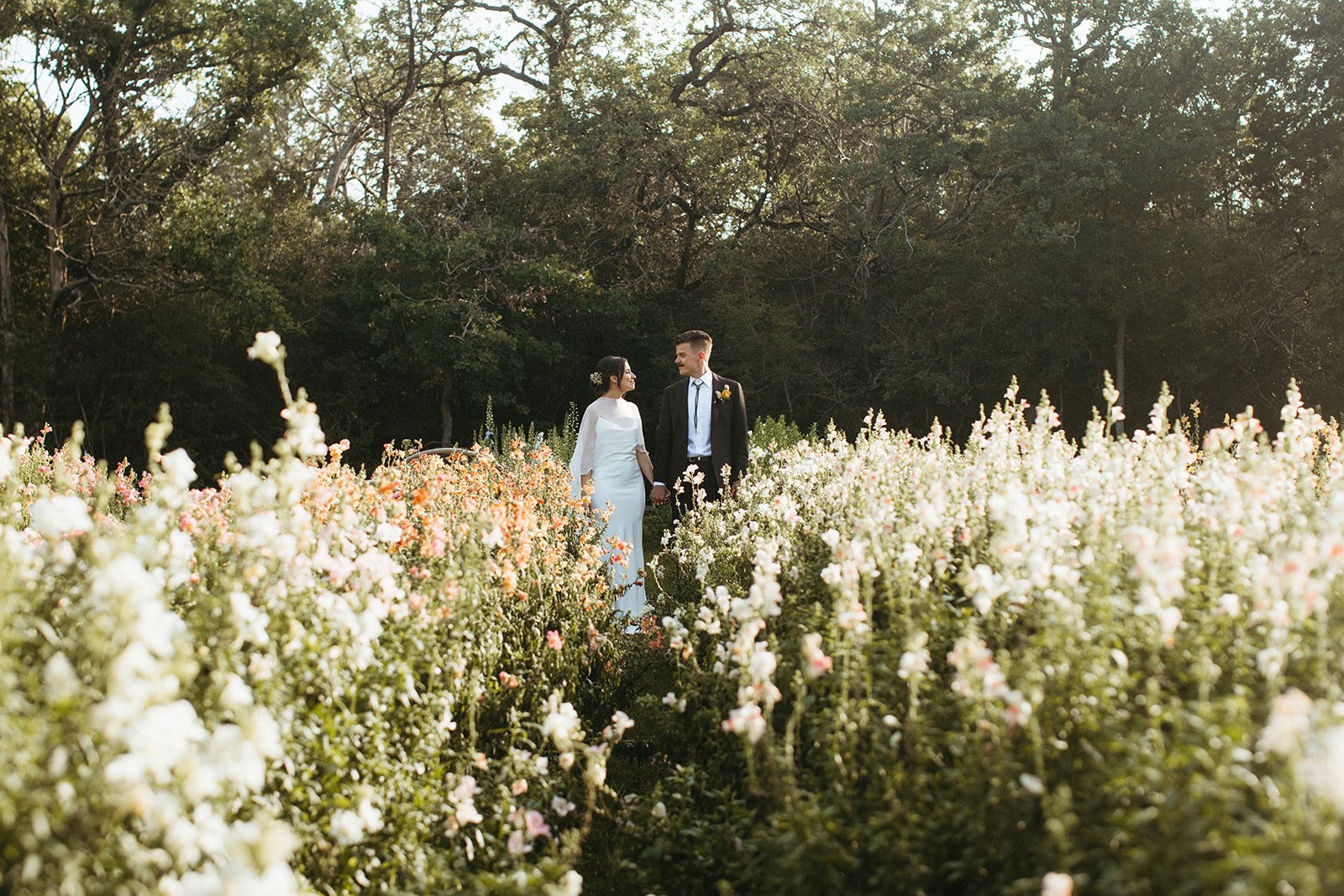 Bride and groom walking through the working flower farm at The Grand Lady wedding venue in Austin, Texas.